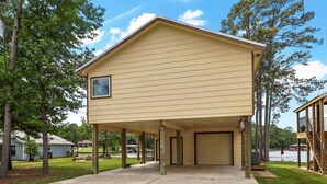 Een gebouw met twee verdiepingen, een overdekte veranda, een garage en uitzicht op een meer.