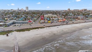 A coastal cityscape with a beach, a prominent red landmark, and a mix of residential and commercial buildings.