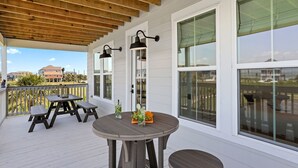 Une terrasse extérieure couverte avec une plateforme en bois, une table ronde entourée de chaises et de grandes fenêtres offrant une vue sur les environs.