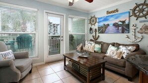 A living room with a sofa, coffee table, and a painting of a beach scene.