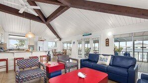 A spacious living area with a red coffee table, blue sofa, and patterned chairs. - Sea Isle Sailfish! Canal front in popular Sea Isle! Pet Friendly! (Galveston)