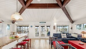 A spacious kitchen with a bar area, a dining set, and a living area with a sofa and chairs. - Sea Isle Sailfish! Canal front in popular Sea Isle! Pet Friendly! (Galveston)