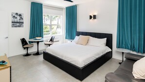 A modern hotel room with a large bed, a desk, and a chair. - Remodeled Beachfront Studio w/ Beach Essentials. Just steps from the beach!  (Miami Beach)