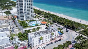 An aerial view of a coastal hotel with a pool, beach access, and a parking area. - Remodeled Beachfront Studio w/ Beach Essentials. Just steps from the beach!  (Miami Beach)