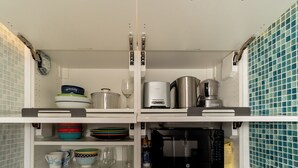 A kitchen with white cabinets, a microwave, a coffee maker, and various dishes and utensils. - Remodeled Beachfront Studio w/ Beach Essentials. Just steps from the beach!  (Miami Beach)