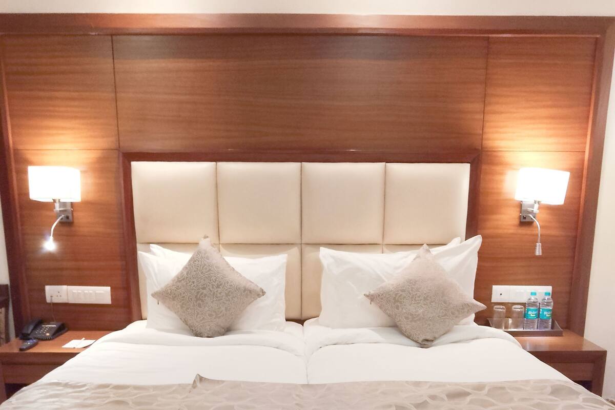 A double bed with a wooden headboard, two bedside tables with lamps, and a bedside phone.
