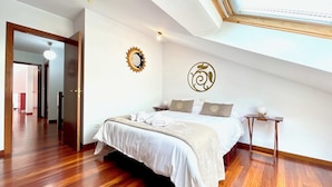 A bedroom with a bed, two bedside tables, a wall clock, and a ceiling light. - The Cliffs - ViveMare (Viveiro)