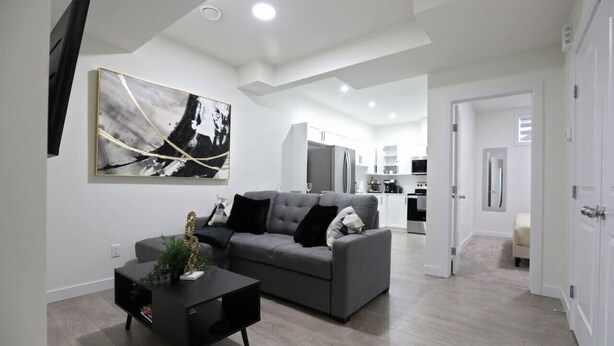 A modern living room with a grey sofa, black coffee table, and a large abstract painting on the wall. - Elegant Escape w/King Bed|Long Stays|WEM|Disney+ (Edmonton)