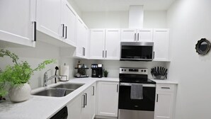 A modern kitchen with white cabinets, stainless steel appliances, and a dishwasher. - Elegant Escape w/King Bed|Long Stays|WEM|Disney+ (Edmonton)