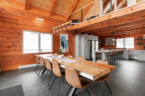 Una cocina moderna con armarios blancos, un refrigerador de acero inoxidable y un comedor con una mesa y sillas de madera.