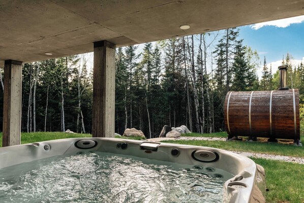 Un jacuzzi con vistas a un bosque y un barril de madera.