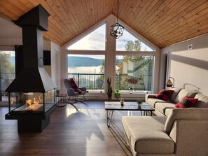 A spacious living room with a large fireplace, a sofa, a coffee table, and a view of the outdoors.