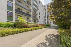 En flerplansbolig med altaner, en belagt sti og grønne områder.