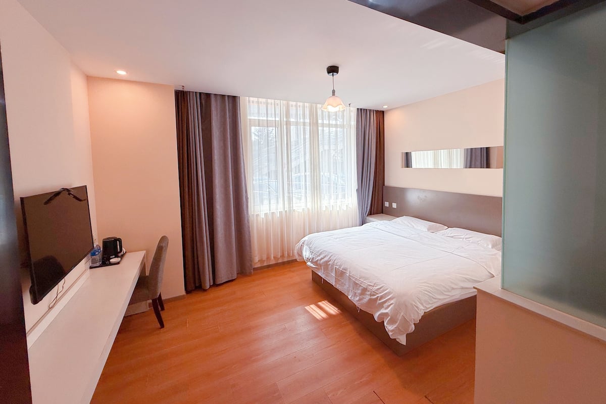 Ein modernes Hotelzimmer mit Bett, Schreibtisch und Fernseher.