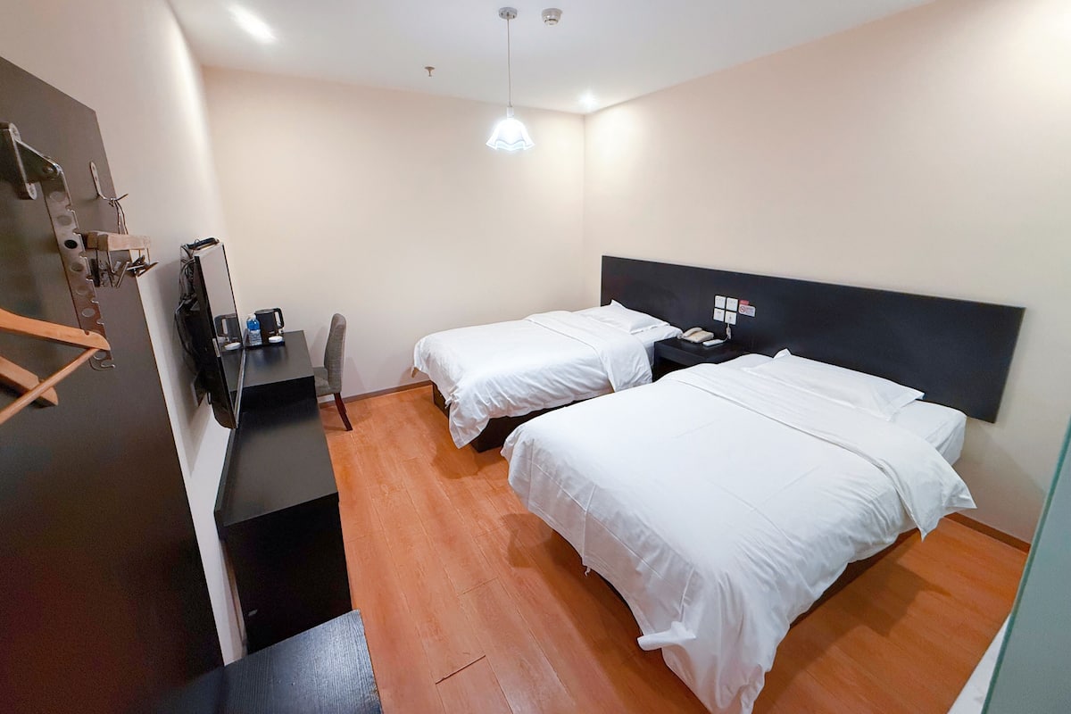 Ein Hotelzimmer mit zwei Betten, einem Schreibtisch und einem Stuhl.