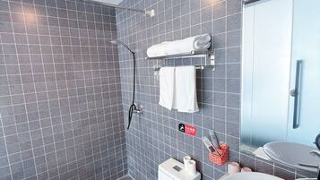 Un baño moderno con paredes de azulejos grises, un inodoro blanco, una ducha y un lavabo con espejo.