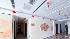 A hotel corridor with a marble wall, a sign indicating room numbers, and red lanterns. - Morning Wind Urban Hotel （May Fourth Square Branch) (Qingdao)