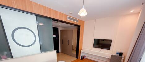 A hotel room with a bed, a TV, a desk, and a large mirror.