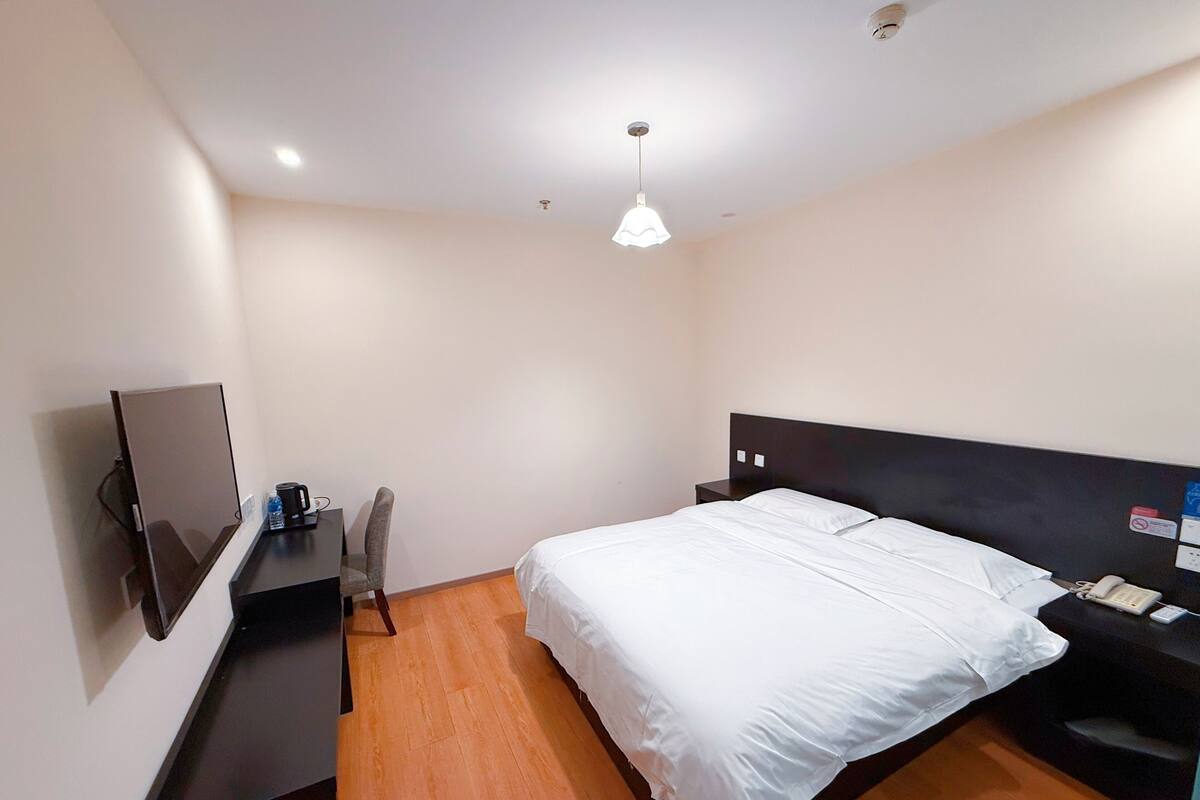 Ein Hotelzimmer mit Bett, Schreibtisch, Stuhl, Fernseher und Telefon.