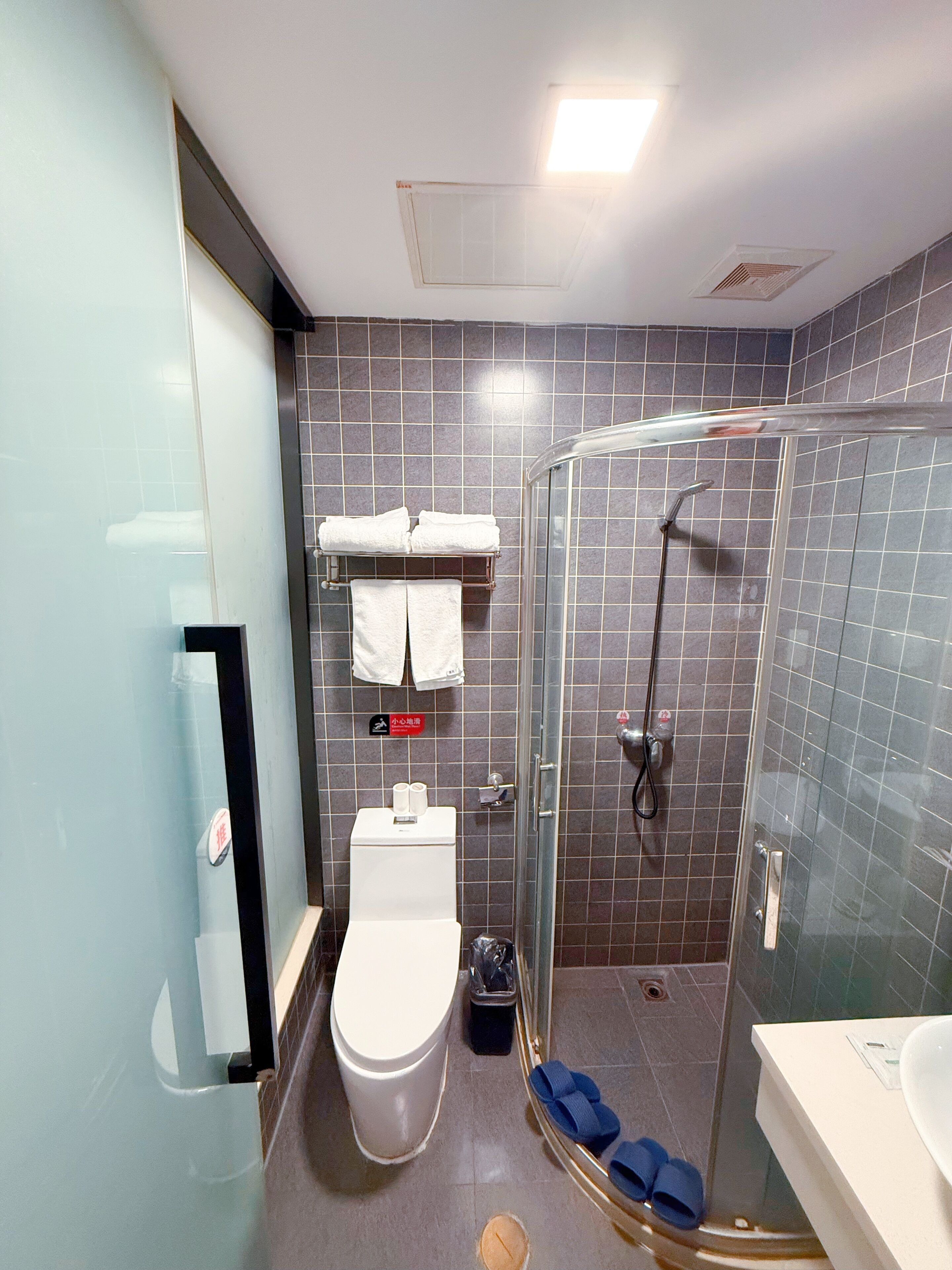 Un baño moderno con inodoro, cabina de ducha de vidrio y lavamanos.