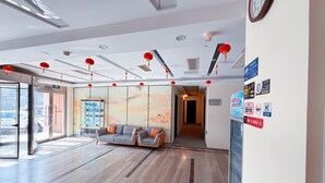 A modern lobby with a reception desk, seating area, and a glass door entrance. - Morning Wind Urban Hotel （May Fourth Square Branch) (Qingdao)