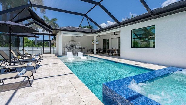 Una piscina interior moderna con sillones de descanso y un área de patio con paredes de vidrio.