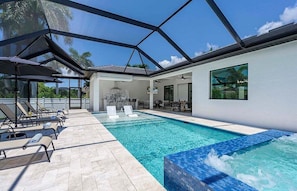 Una piscina interior moderna con sillones de descanso y un área de patio con paredes de vidrio.