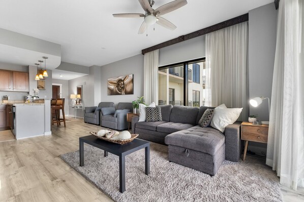 Un salon moderne avec un canapé gris, une table basse et un ventilateur de plafond.