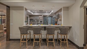 Une cuisine moderne dotée d’un îlot central, de tabourets de bar et d’un coin repas avec une table et des chaises.