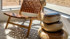 Una habitación con un ventanal grande, un sillón de fibras naturales y una pila de cuencos de madera.