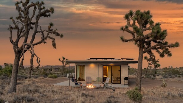 Una casa moderna con un brasero, asientos exteriores y vistas al paisaje desértico.