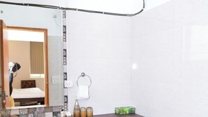 A bathroom with a sink, vanity, mirror, and toilet. - Arkaya Inn (Gurugram)
