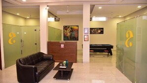 A lobby with a reception desk, a pool table, a sofa, and lockers. - Arkaya Inn (Gurugram)