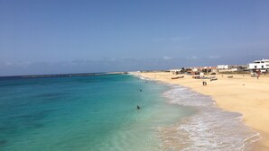 A beach with clear turquoise waters, a sandy shore, and buildings in the background. - 4 Bedroom Private vacation home in Vila do Maio (Vila do Maio)