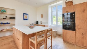 Eine moderne Küche mit einer zentralen Kochinsel, Holzschränken und einem großen Fenster.