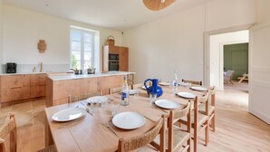 Eine moderne Küche mit Holzausbau, einer zentralen Kochinsel und einem Essbereich mit einem Holztisch, gedeckt für vier Personen.