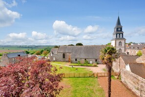 A historic building with a clock tower, surrounded by a grassy courtyard and stone walls. - Family house for 8 adults and 6 children (Pléboulle)