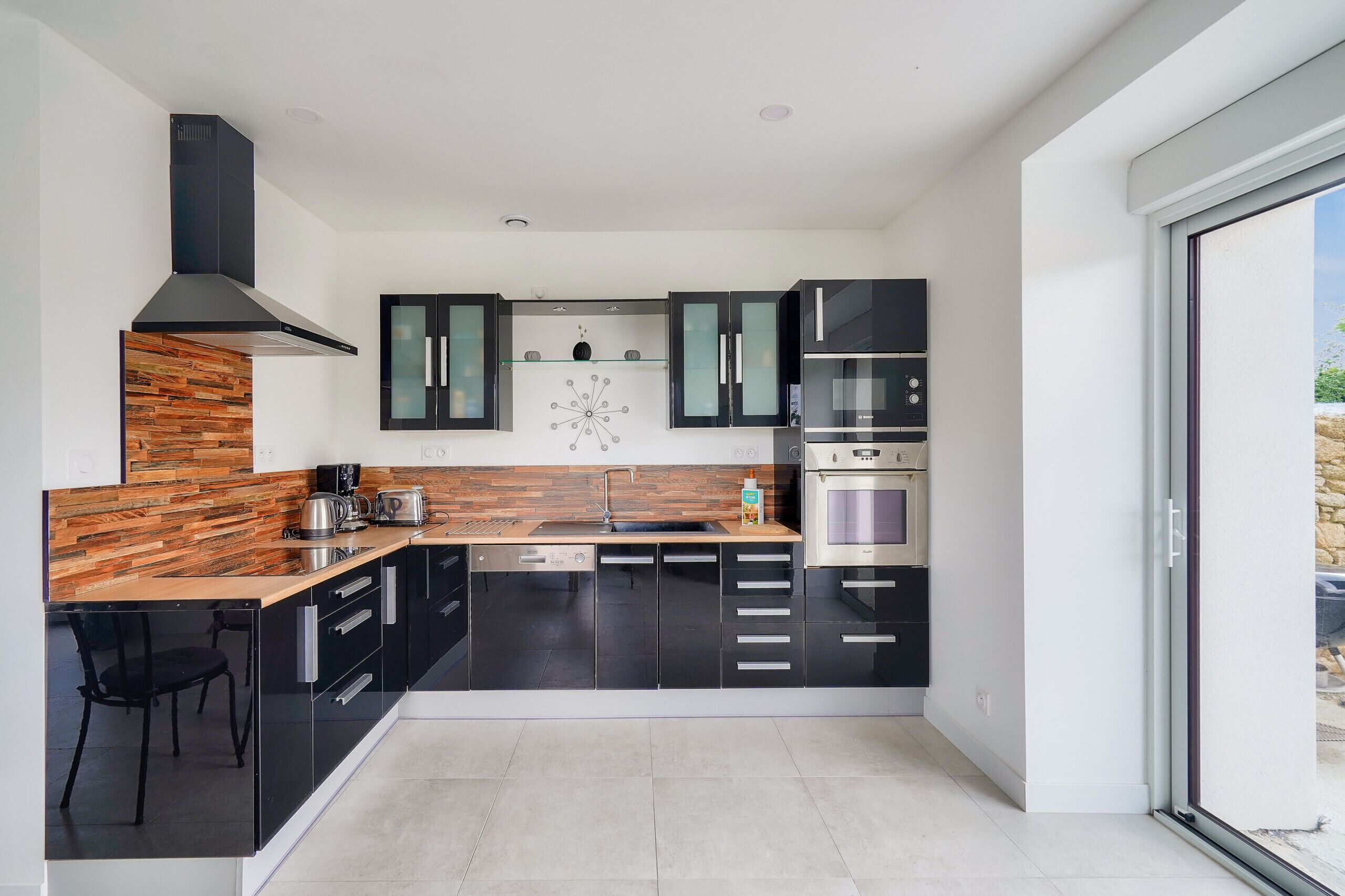 Eine moderne Küche mit schwarzen Schränken, einer Holz Arbeitsplatte und einem eingebauten Backofen.