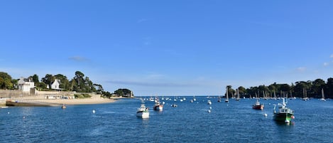 Una marina costera con barcos amarrados y una playa arenosa al fondo.