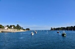 Un port de plaisance situé sur la côte, avec des bateaux amarrés et une plage de sable en arrière-plan.