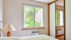 Un dormitorio con cama, ventana, radiador y lámpara.