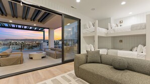 A modern living room with a sofa, a round coffee table, and a view of a cityscape through large glass doors.