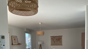 A dining area with a table, chairs, a hanging wicker light fixture, a map on the wall, and a window.