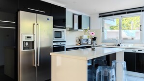 Eine moderne Küche mit Edelstahl-Kühlschrank, Einbauofen, Mikrowelle und einem großen Fenster für natürliches Licht.