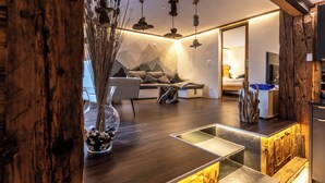 Een moderne woonkamer met een houten vloer, een bank met kussens, een salontafel en een decoratieve vaas met stenen.
