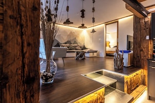 Una sala de estar moderna con piso de madera, un sofá con cojines, una mesita de centro y un jarrón decorativo con piedras.