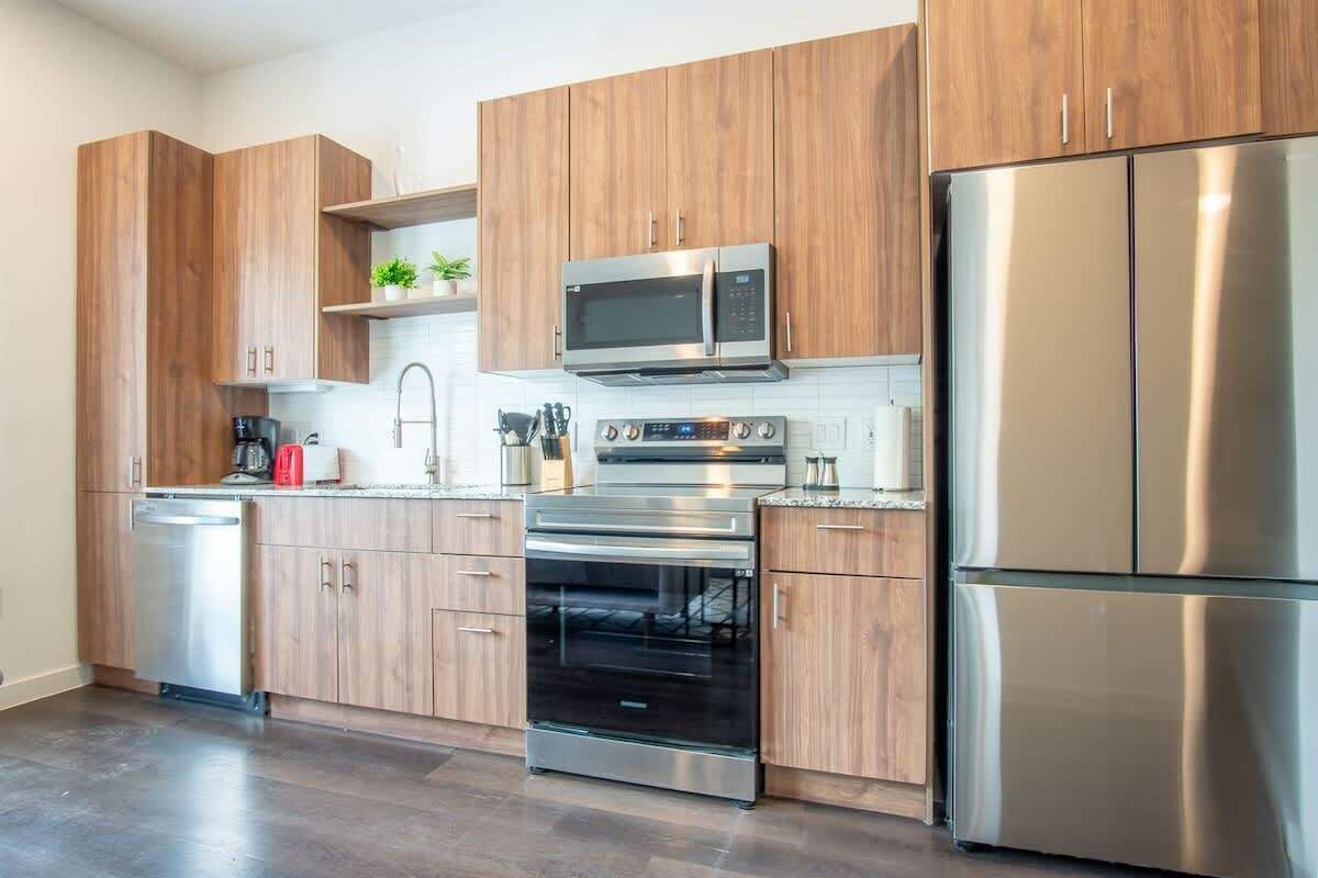 A modern kitchen with wooden cabinets, stainless steel appliances, and a dishwasher.