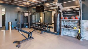 Een sportschool met gewichthefapparatuur, een bokszak en een kettlebellrek.