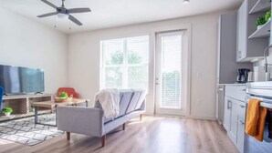 Een moderne woonkamer met een bank, televisie en een eethoek.