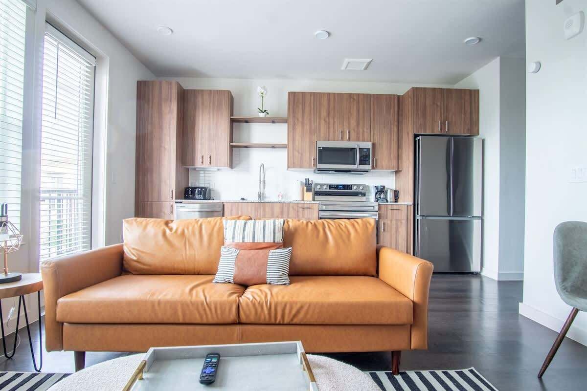 A modern kitchen with wooden cabinets, a microwave, oven, and refrigerator.